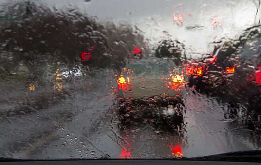 Road view through car window with rain drops