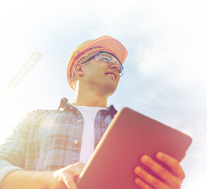 A construction foreman in a hard hat with an electronic tablet