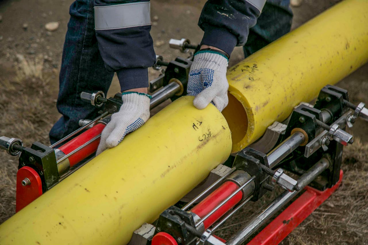 Person in construction gloves fitting yellow pipes