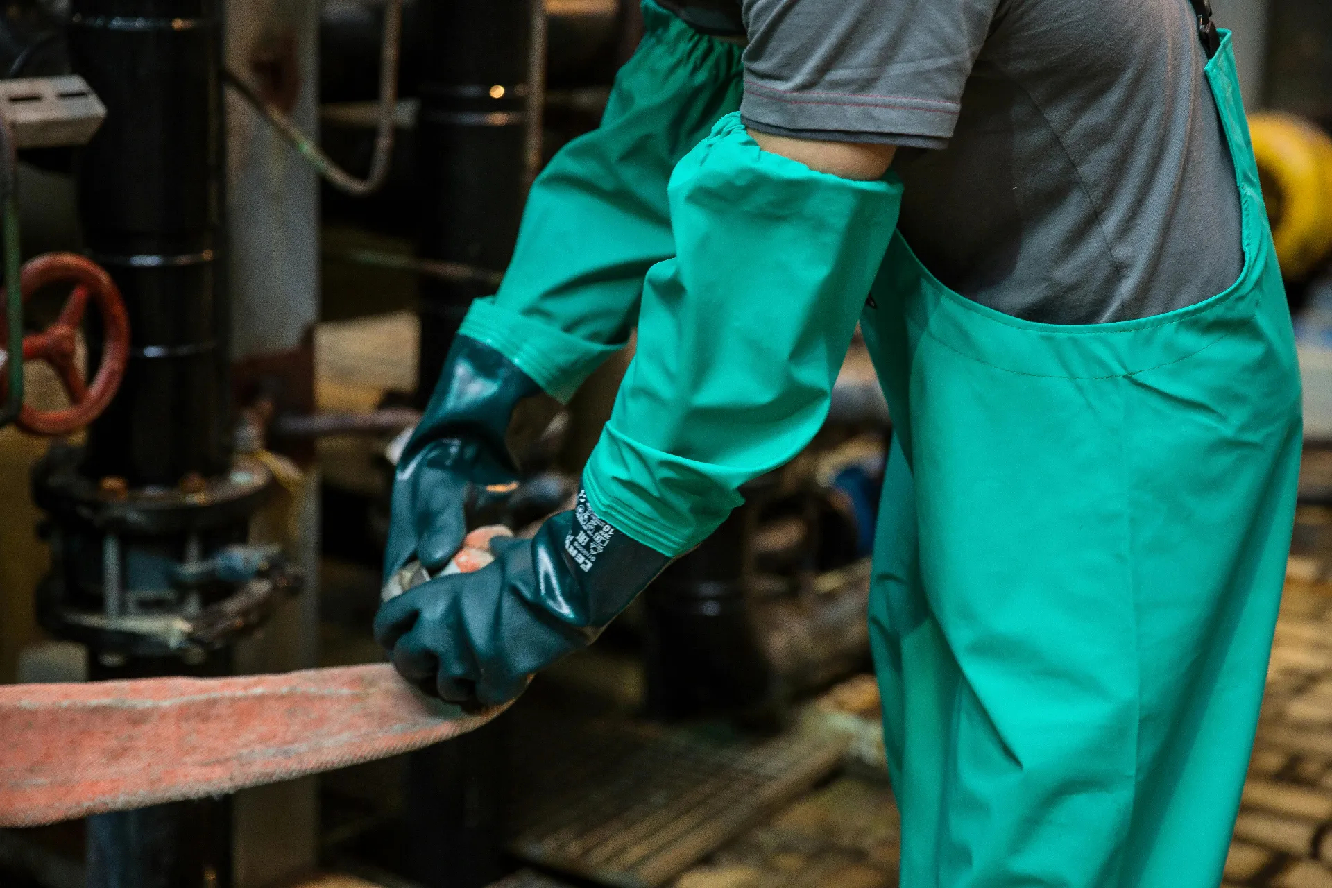 person working in green protective clothing and gloves